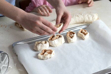 Children mold cheesecakes from dough. Kitchen table in flour. Warm relationships children.