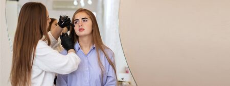 Female cosmetologist performs eyebrow correction on beautiful models in the beauty parlor....