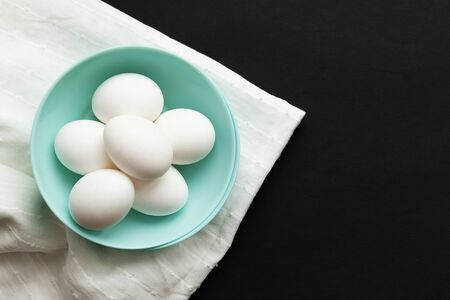 Traditional easter food eggs. Colored dishes on a White napkin and black background. Minimalistic design. Colors Trend 2020.の写真素材