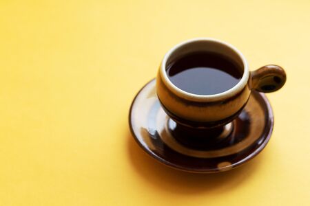 A cup of tea or coffee on a yellow table. Minimalism. Lunch or lunch break. Time to rest. Good...