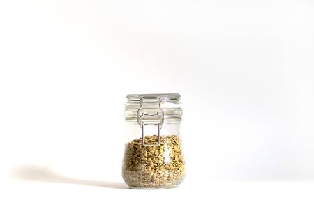 Green lentils tightly closed in a glass bowl. One jar stands on a white background in daylight with shadows. Safe and environmentally friendly storage of legumes. Food stocks for future use.の写真素材