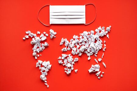 A mask of white paper lies on a red background with the image of a world map. Concept - personal...