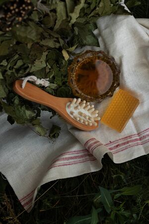 Bath soap lies on a light towel. A birch broom, a body brush and natural honey lie nearby. Set of accessories for sauna and steam room. The concept of returning to the roots of life.の写真素材
