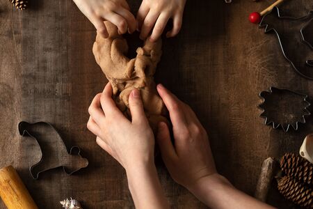 Children play with salt dough on the kitchen table. Hands mold clay with their own hands to create...