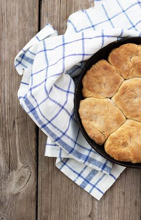 Fresh homemade wholemeal bread in metal baking dish. Wooden background, fabric napkin and spatula lie nearby.の写真素材