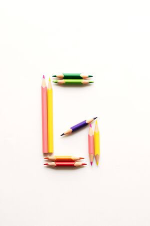 Letter G composed of colored pencils on white paper.の写真素材
