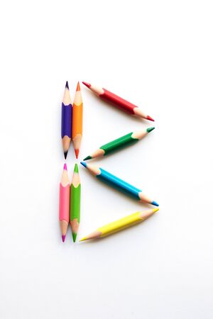 Letter B composed of colored pencils on white paper.の写真素材