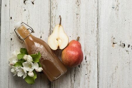 Bottle of apple and pear juice, fresh pears and flowers on a wooden background. Country style.の写真素材
