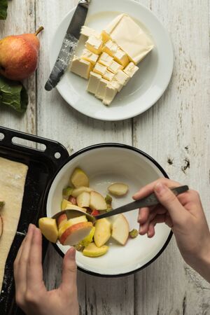 Girl lays out the filling on puff pastry. Making rhubarb and pear pie.の写真素材