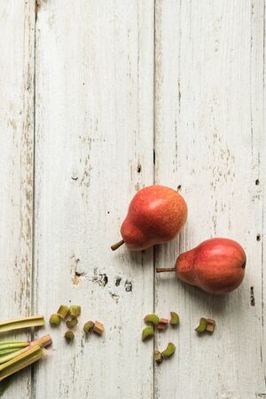 Rhubarb stalks and two pears on a white wooden background. Complementary colors. Grass and fruit.の写真素材
