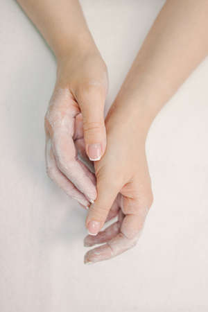 Female hands in white cream, on a white background.の写真素材