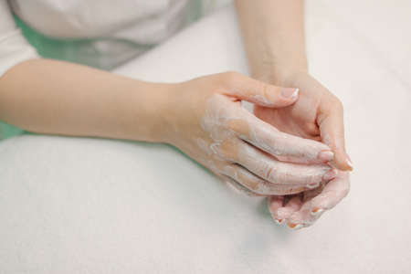 Female hands in white cream, on a white background.の写真素材