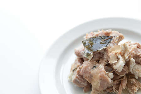 Braised pork on a white plate with bay leaves, white backgroundの写真素材