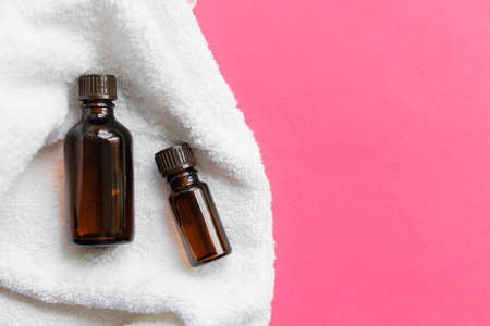 2 jars of brown glass with oil lie on a white towelの写真素材