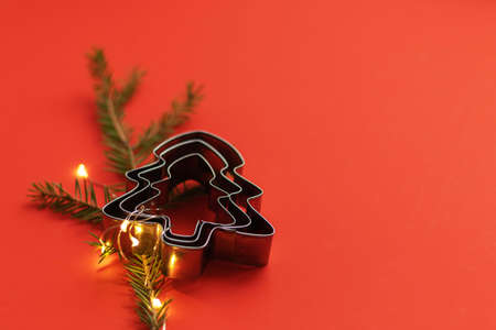 Christmas tree in the shape of cookies. Red background and minimalism. New Year greetings and kitchen toolsの写真素材