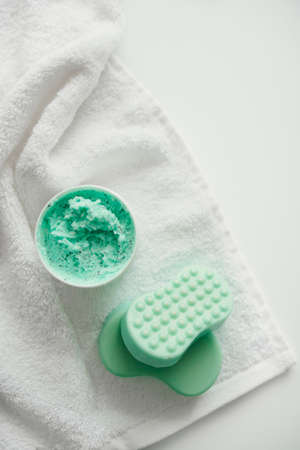 Scrub and two sea-green soaps lie on a white towel, flat layの写真素材