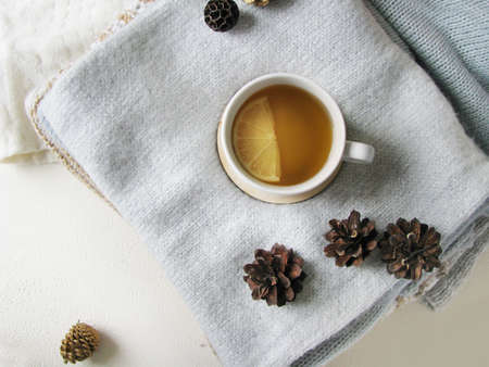 Christmas and happy winter holiday. Warm cozy home. Soft knits, pine cones, and a cup of lemon tea. View from aboveの写真素材