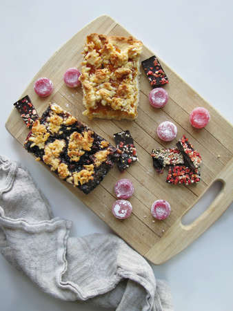 Pieces of pie with jam, and chocolate with nuts on a wooden boardの写真素材