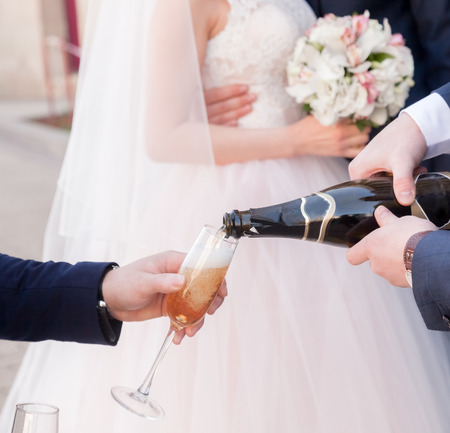 Two men pouring Champagne outdoors hands closeup weddingの写真素材