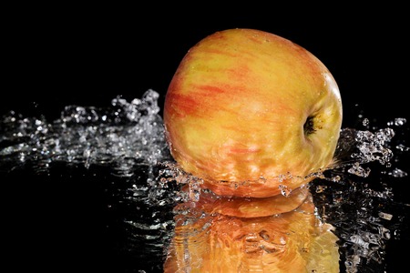 red apple under a waterfall splashing on a backgroundの写真素材