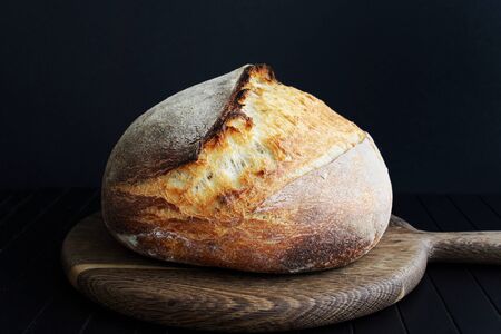 Sourdough bread on wooden cut board on black backgroundの写真素材