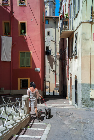 Woman with two dogs walks in an old townの写真素材