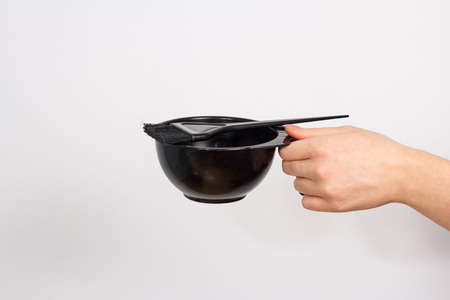 Black bowl and paint brush on the woman's handの写真素材