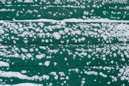The texture of wooden wall painted green paint and covered with snow.の写真素材