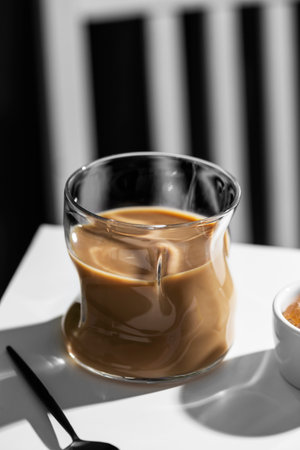 Coffee in a glass cup on a white table in sunlightの写真素材