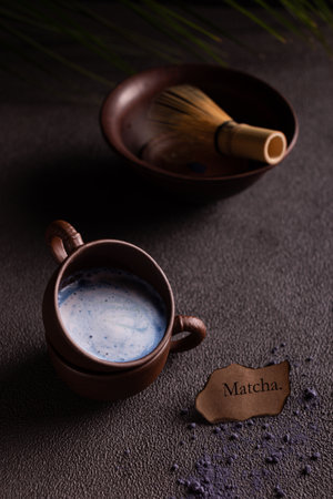Cup of matcha latte and matcha powder on black backgroundの写真素材