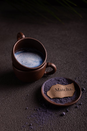 Cup of matcha latte with matcha powder on dark backgroundの写真素材