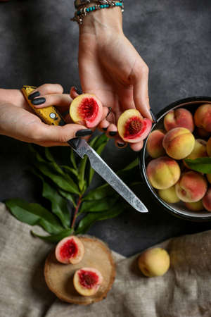 girl holding peaches and a knife in her handsの写真素材