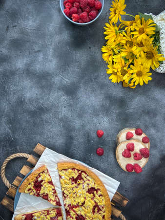 pie with raspberries and yellow flowers on a dark backgroundの写真素材