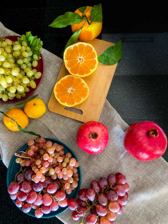 Bright and juicy orange, green and red grapes, tangerines and pomegranateの写真素材