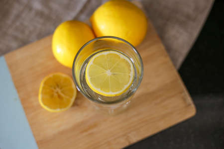 glass cup with water and lemon on wooden boardの写真素材