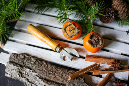 bottle opener, cinnamon sticks and bright persimmon on a wooden trayの写真素材
