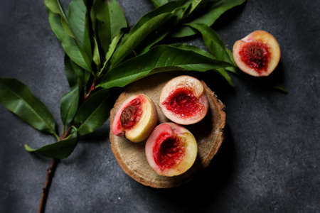 small cut peaches and peach tree leaves on a dark backgroundの写真素材