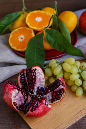 cut pomegranate, grapes and juicy tangerinesの写真素材