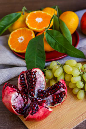 healthy fruits: pomegranate, oranges and grapes on the kitchen table