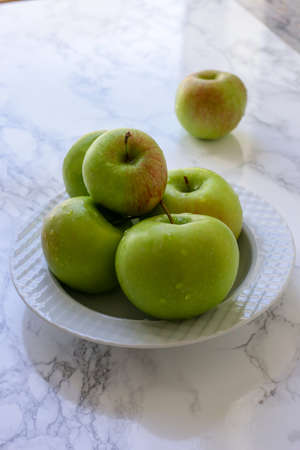 green, healthy apples in a white plateの写真素材