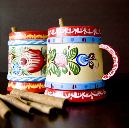 two wooden mugs painted with cinnamon tea on a dark background