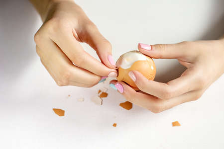 Photos of beautiful elegant women's hands with manicure that clean a boiled egg. Keto diet. Good...
