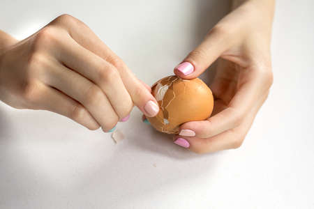 Photos of beautiful elegant women's hands with manicure that clean a boiled egg. Keto diet. Good nutrition. Healthy food. Farm.の写真素材