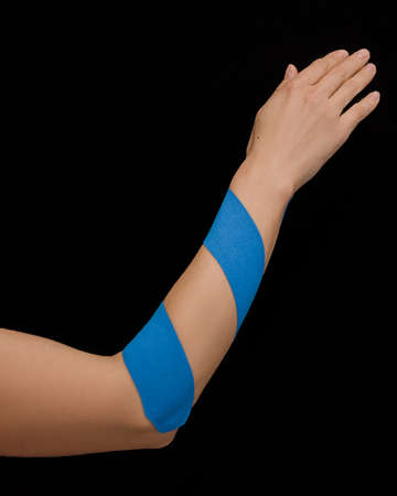 Kinesio tape on female hand isolated on black background. Chronic pain, alternative medicine. Rehabilitation and physiotherapy. Photoの写真素材