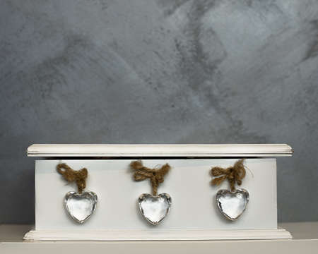 Three glass hearts in white wooden box on gray background. Like three friends, mother father and son or doughter. Copy spaceの写真素材