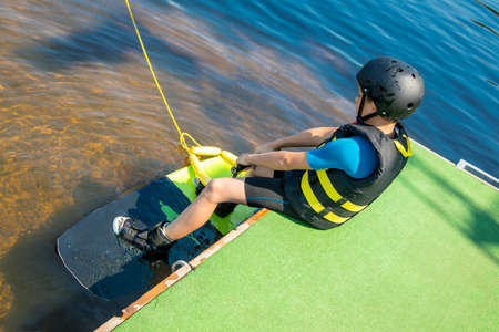 A small Caucasian boy of 10 years old in a protective suit, active wakeboard training with fun activities in water sports adventure, relaxation and exercise concept. Sports and Hobbiesの写真素材