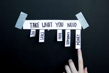 ad with the inscription Take what you need. A woman's caucasian hand reaches for one of the words to make a choice love grace romance pride money. Photo for your articles about psychology, lifestyleの写真素材