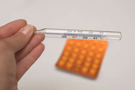 Mother doctor hand holding mercury thermometer with a high temperature against the background of a...