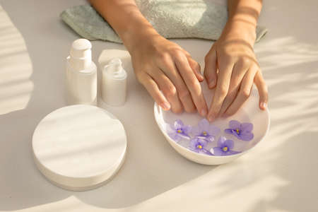 Elegant, well-groomed female hands with long fingers. Skin care procedure for hands, nails, manicure. Concept of Spa beauty salon. Beautiful play of shadows, light on table. Cream for handの写真素材
