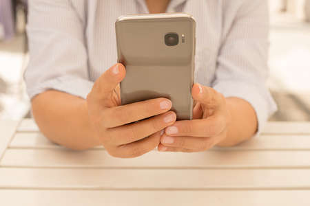 Close up photo of womens hands holding cell telephone business woman writing sms during coffee break...